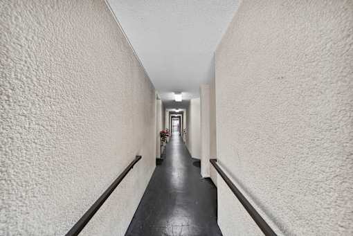 A long hallway with white walls and a black floor.