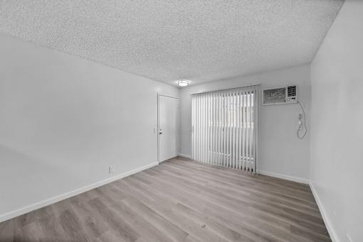 A room with a wooden floor and a window with blinds.