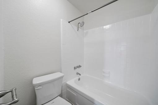 A white bathroom with a toilet, tub, and shower.