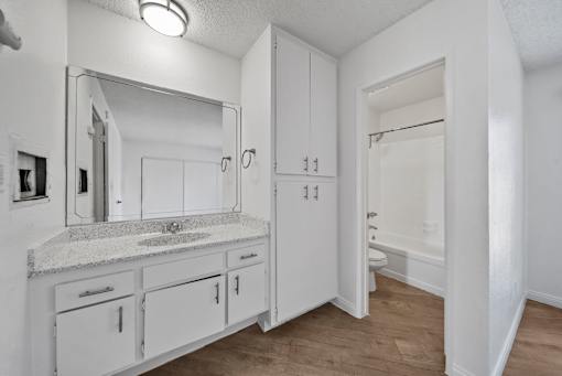 A bathroom with a sink, mirror, and cabinets.