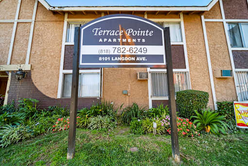 A sign for Terrace Pointe Apartments stands in front of a building.