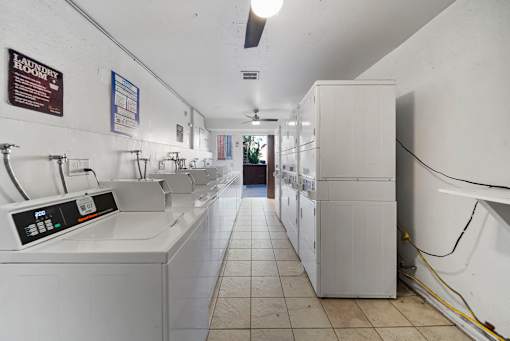 A laundromat with washers and dryers lined up.