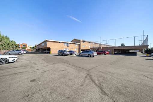 A parking lot with several cars and a building in the background.
