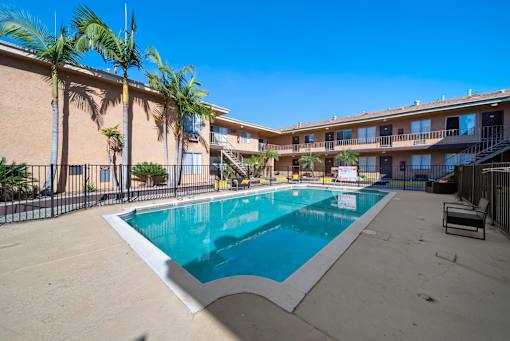 A swimming pool surrounded by palm trees and a building.