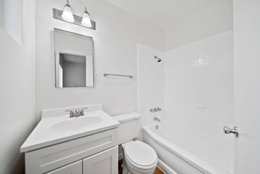 A white bathroom with a toilet, sink, and bathtub.