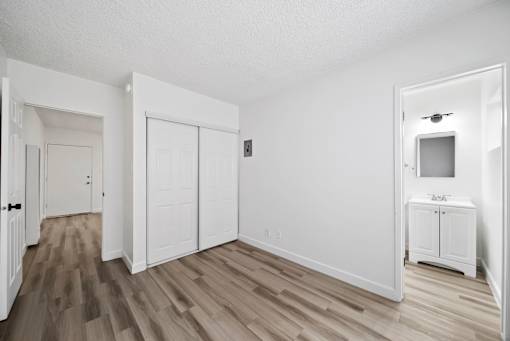 A white room with a wooden floor and a small white cabinet.