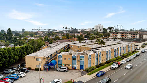 A parking lot with cars and a yellow building with blue doors.