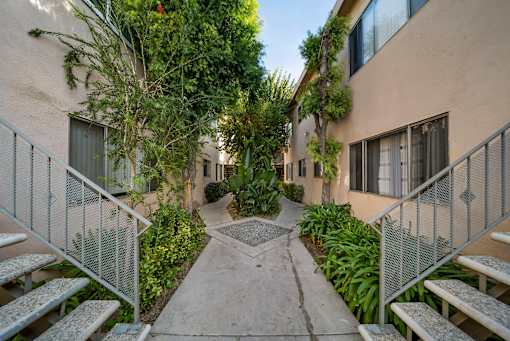 A pathway leads through a courtyard with a metal fence on either side.