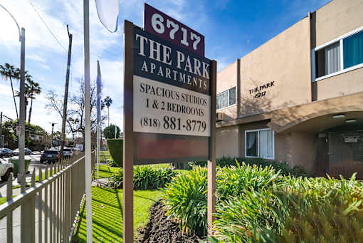 A sign for 6717 The Park Apartments is displayed in front of a building.