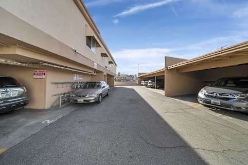 A parking lot with cars parked on both sides of the road.