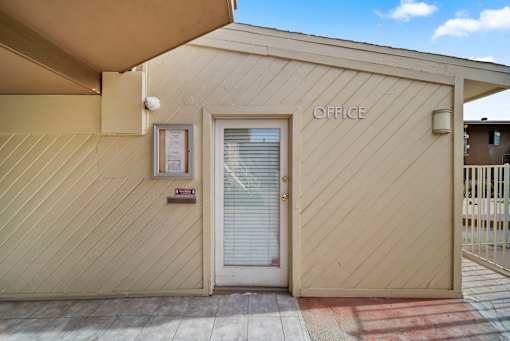 A small office building with a white door and a sign on the wall.