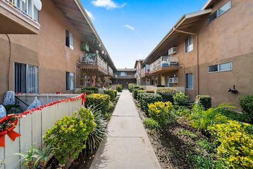 A sunny day in a residential area with apartment buildings on either side of a walkway.