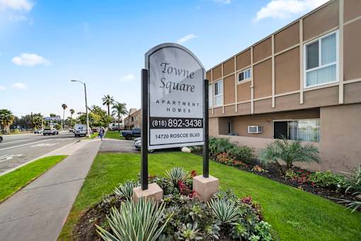 A sign for apartment homes with a phone number and address.