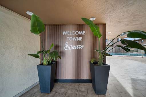 A sign that says "Welcome to Wyne Square" is on a wall.