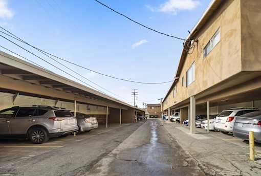 A parking lot with cars parked on both sides of the road.
