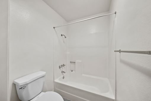 A white toilet and bathtub in a bathroom.
