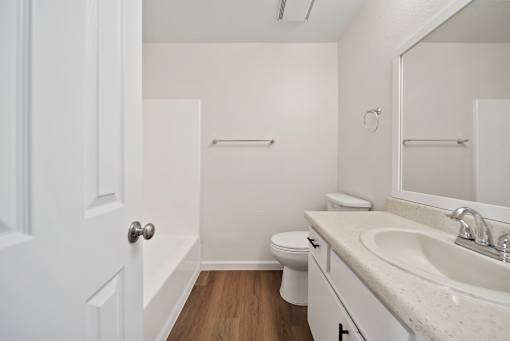 A white bathroom with a toilet, sink, and mirror.