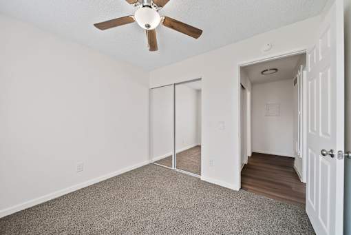A room with a ceiling fan and sliding doors.