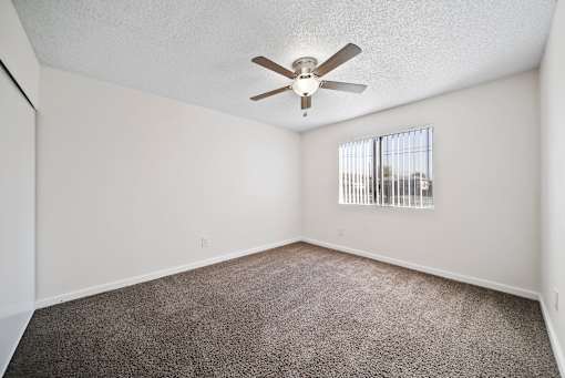 A room with a ceiling fan and carpeted floor.