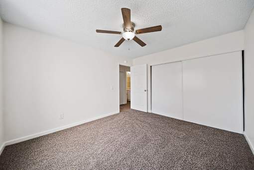 A room with a ceiling fan and carpeted floor.