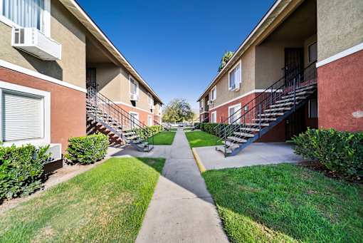A pathway leads between two rows of apartment buildings.