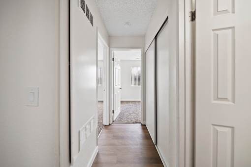 A long hallway with white walls and wood floors.