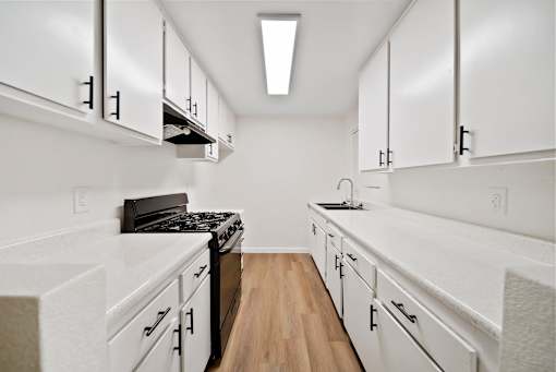 A kitchen with white cabinets and a black stove top oven.