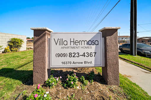 A sign for Villa Hermosa Apartment Homes with a phone number and address.