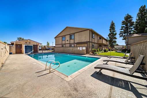 A pool with a slide and sun loungers in front of a building.