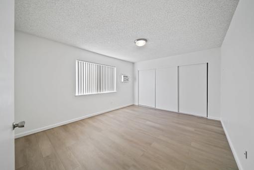 A room with a white ceiling, a radiator on the wall, and a wooden floor.