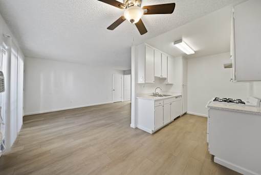 A kitchen with white cabinets and a wooden floor.