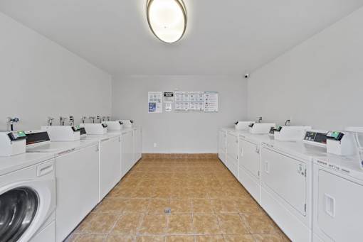 A laundromat with a row of washers and dryers.