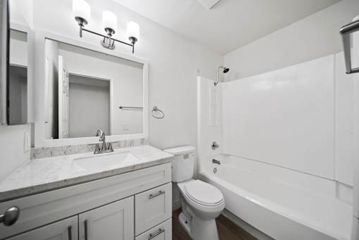 A white bathroom with a toilet, sink, and bathtub.