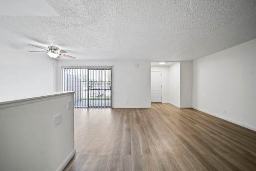 A room with a ceiling fan and a wooden floor.