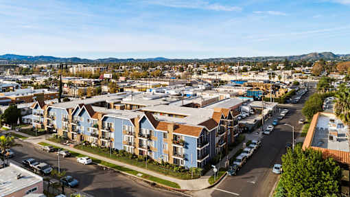 A view of a residential area with apartment buildings and cars parked on the street.