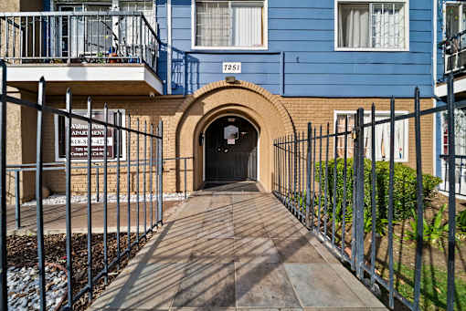 A blue building with a black gate and a wooden walkway leading to a tunnel entrance.