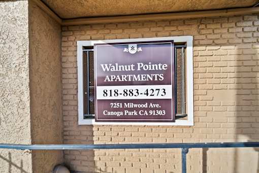 A sign for Walnut Pointe Apartments is on a building.
