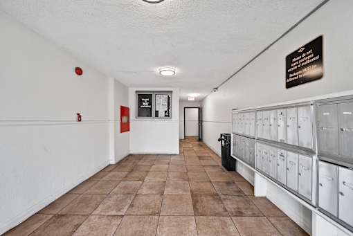 A long hallway with a sign on the wall and mailboxes on the right.