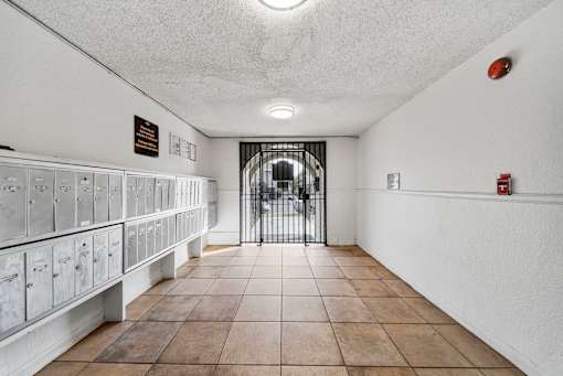 A long hallway with a metal gate at the end and mailboxes on the left.