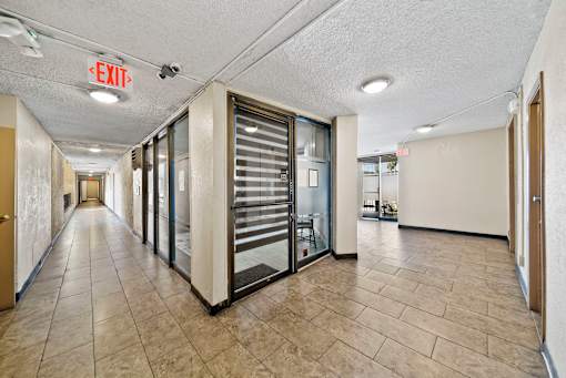 A long hallway with a red exit sign on the ceiling.