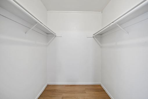 A white room with wooden floors and two white shelves.