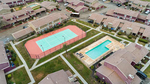 A tennis court is surrounded by houses.