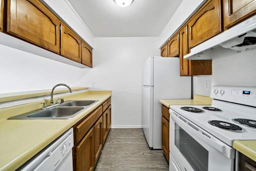 A kitchen with white appliances and wooden cabinets.