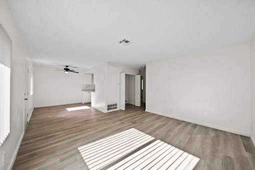 A room with a ceiling fan and a rug on the floor.