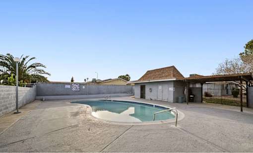 A small pool in a backyard with a building in the background.
