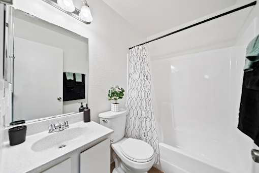 A white bathroom with a toilet, sink, and shower.