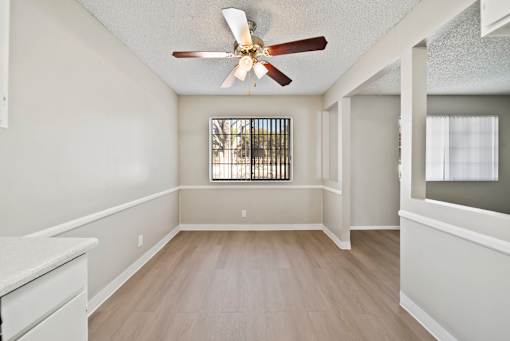 A room with a ceiling fan and a window with bars.