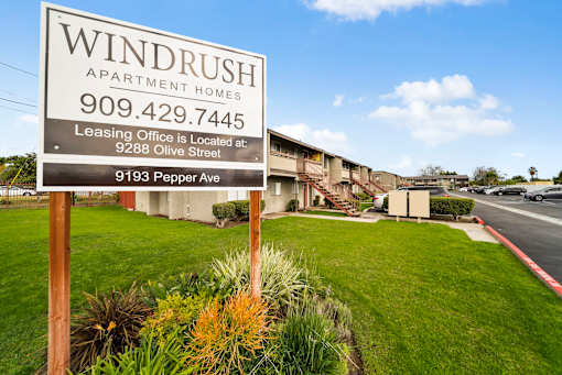 A sign for Windrush Apartment Homes is in front of a building.