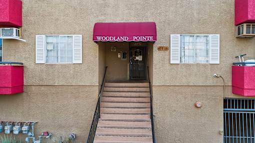 The entrance to a building with a red awning that says Woodland Pointe.