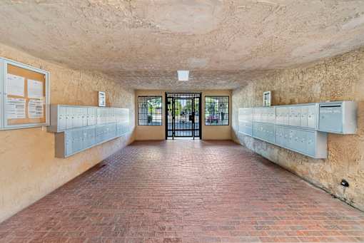 A long hallway with a brick floor and white lockers on the wall.